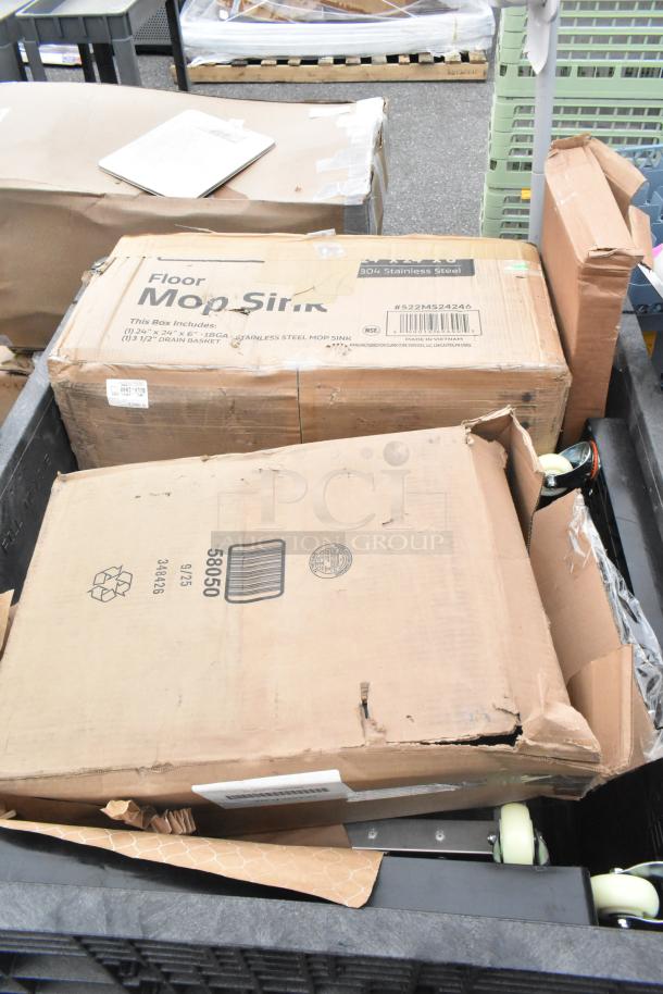 Boxes containing brand new scratch and dent items, including a mop sink. Packaging shows minor wear. Labels display model and specifications.