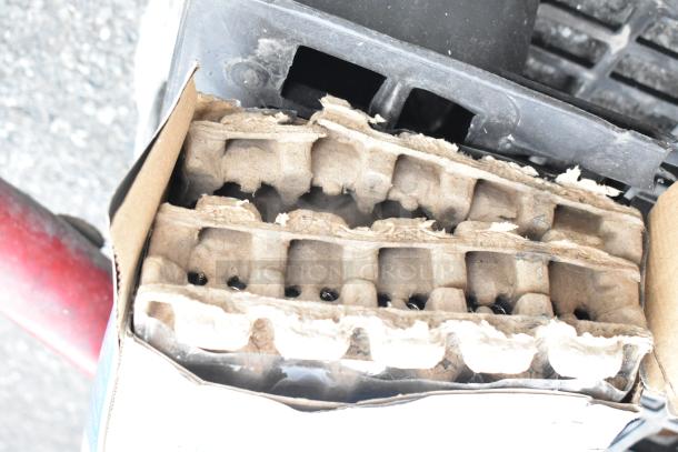 Two red metal round tables with attached seats, showing durable construction; cardboard packaging visible.