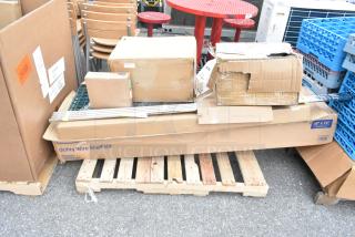 Six brand new scratch and dent items, including dish caddies, in boxes on a pallet. Utility Wire Shelf Kit visible label.