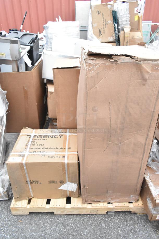 New scratch and dent items on a pallet, including a Regency sink box, assorted packaging, and a dunnage rack.