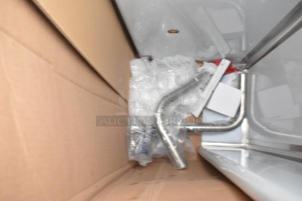 Three scratch and dent items, including a new sink and dunnage rack, in a cardboard box with protective wrap.