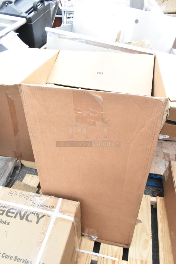 Cardboard boxes containing brand new scratch and dent items, including a sink and dunnage rack, on a wooden pallet.