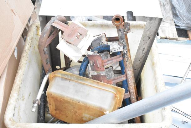 White poly bin containing various metal and plastic parts, showing signs of rust and wear. Mixed industrial contents.