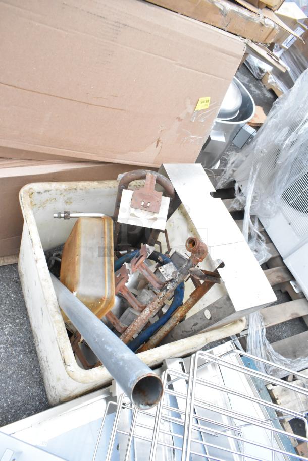 White poly bin filled with assorted metal items, rusted and varied in size. Bin shows signs of wear and outdoor use.