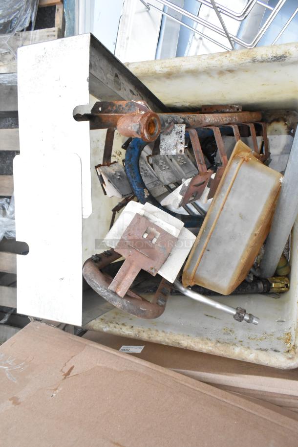 White poly bin filled with mixed metal parts and tools, showing rust and wear. Includes hoses, fittings, and metal scraps.