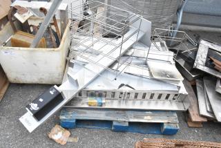 Pallet lot with various stainless steel items and a metal rack in used condition on a blue pallet.