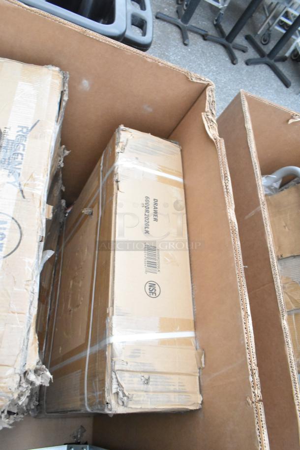 Cardboard boxes containing brand new scratch and dent items, including a Regency wire shelf and sink with visible labeling.