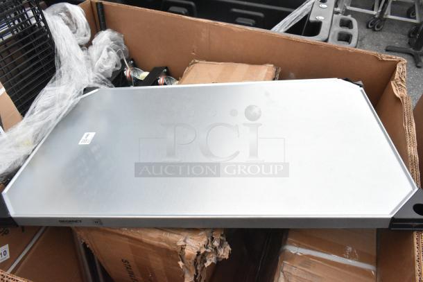 Box of new Regency scratch and dent items including wire shelves and sink. Tags show QR codes for identification.