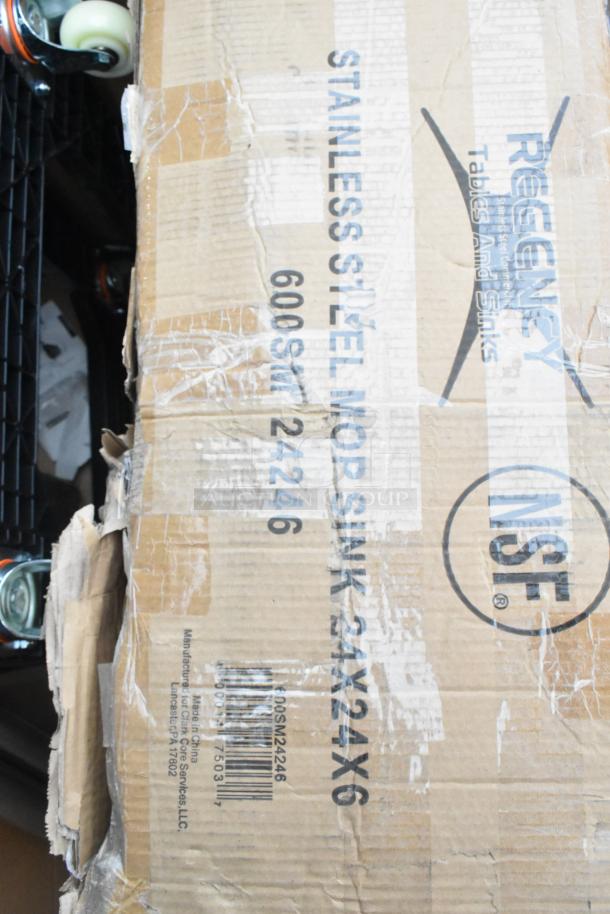 Cardboard box with visible dents labeled "STAINLESS STEEL MOP SINK," "Regency Tables and Sinks," NSF certified. Box contains new items.
