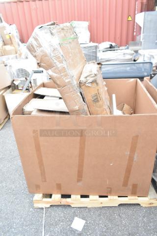Large shipping box containing brand new, scratch and dent items including a host station and dispenser on a wooden pallet.