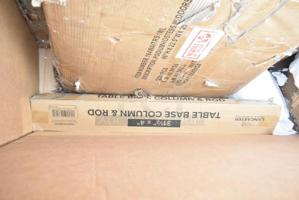 Damaged cardboard packaging containing new table base column and rod set. Visible labels list dimensions and handling instructions.