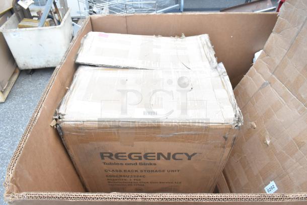 Cardboard box labeled "Regency Tables and Sinks," containing new glass rack storage unit, scratch and dent condition.