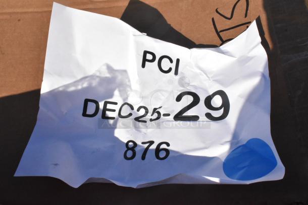 Crumpled paper label marked "PCI DEC25-29 876" with a blue circle on brown background.