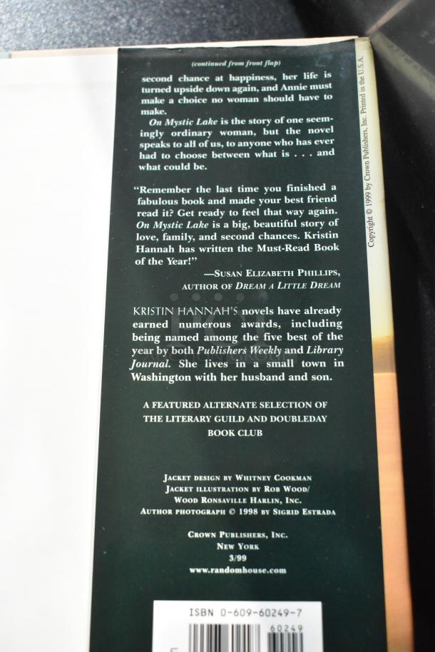 Reverse cover of "On Mystic Lake" by Kristin Hannah, featuring text about the novel's themes and praise quotes. ISBN visible.