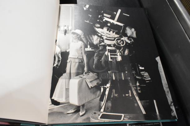 13 assorted books, open to a black-and-white photo of a film set. Variety of genres, gently used condition.