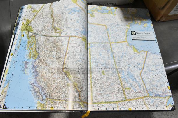 Map book open to a detailed map of Western Canada, highlighting provinces and territories.