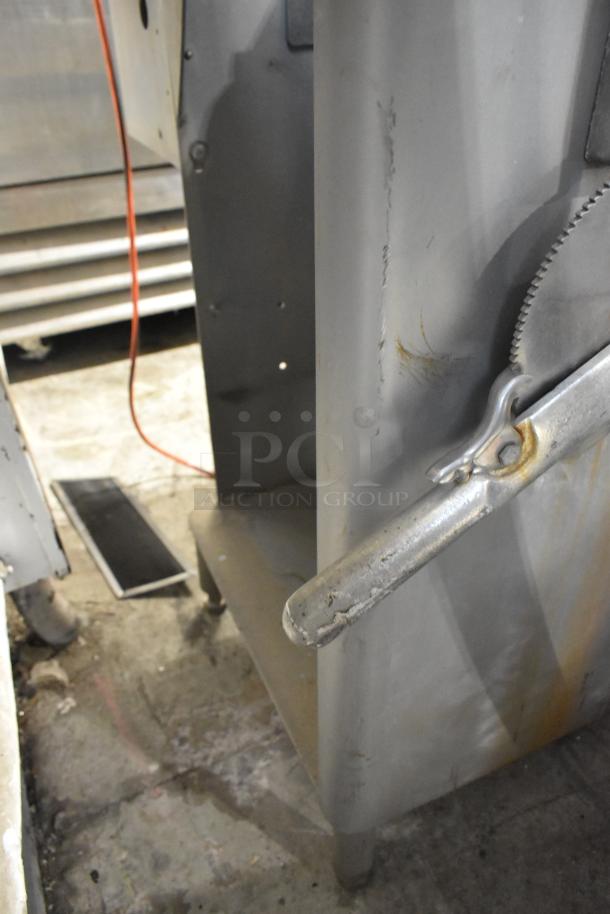 Metal commercial floor-style meat saw, 208 volts, 3 phase. Shows wear and rust, sturdy build for industrial use.