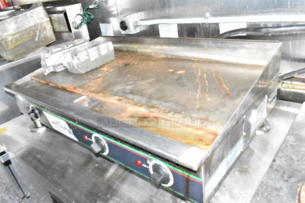 Winco electric flat top griddle in a commercial fast food trailer kitchen, showing dials and cooking surface.