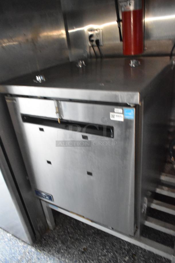 Atosa stainless steel reach-in cooler inside 24' food trailer, with visible power source and fire extinguisher.