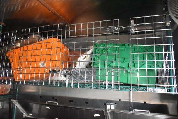 Wire shelf in fast food trailer with orange and green storage bins. Secure, organized setup for kitchen essentials.