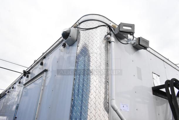 Exterior of a Stuff4less 24' mobile kitchen trailer, featuring surveillance cameras and security lighting.