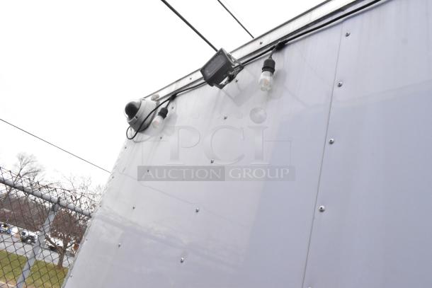 Exterior of a Stuff4less 24' fast food trailer with mounted security camera and lighting fixtures.