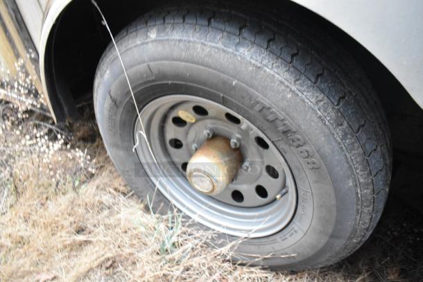 Close-up of a trailer tire with text "TTT 868" visible on the tread, showcasing the trailer's external condition.