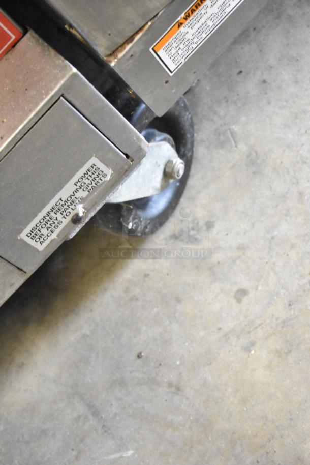 Vulcan VC4GD-10 convection oven base with visible warning and power disconnect labels. Caster wheel shown.