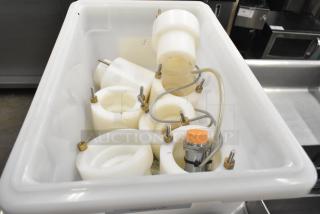 Assorted cookie machine parts in a white bin, including round components with bolts and wires, ready for auction.