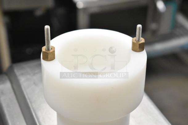 Cookie machine part, cylindrical white plastic with two metal bolts, shown in close-up. Suitable for repair or replacement.