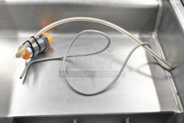 Silver cookie machine part with orange end, attached tubing, on metal surface. Condition appears used. Part of 7-item set.