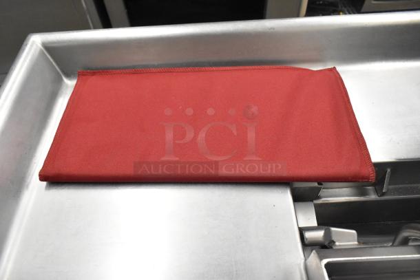 Red mold baking pan liner on a metal surface, part of a seven-item auction lot including countertop signs and Waring panini press grease trap.