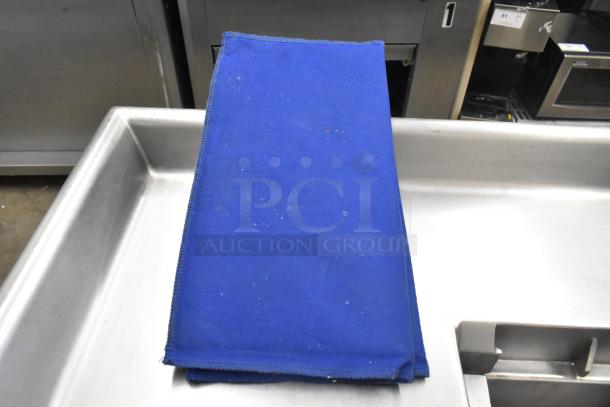 Blue fabric baking pan liner, moderate wear, placed on stainless steel countertop.