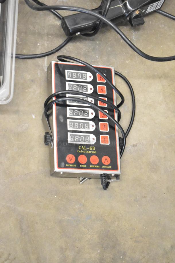 CAL-6B Calculagraph alongside various other items, including utensils and bins. Calculagraph features multiple digital displays and control buttons labeled "Decrease," "Timer," "Reminder," and "Increase." Cords are attached. Appears in used condition.