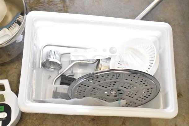 Lot of household items in a bin, includes a timer, metal pan, citrus juicer part, and various metal accessories.