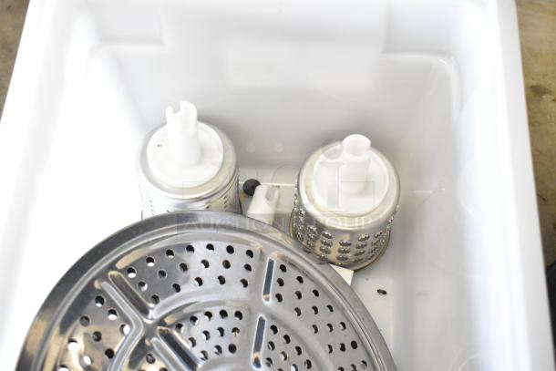 Lot of various kitchen items in a white bin, featuring a perforated metal pan and two metal cylindrical parts with plastic tops.