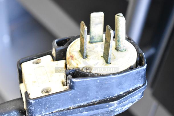 Close-up of the plug for a Fri-jado electric rotisserie oven, showing a 208V, 3-phase power connection with commercial casters.