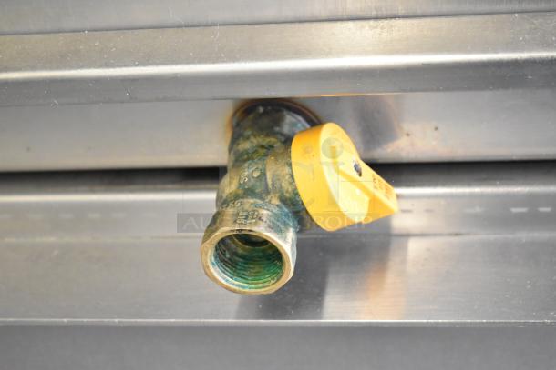 Fri-jado electric rotisserie oven valve; brass with a yellow plastic handle, mounted on stainless steel.