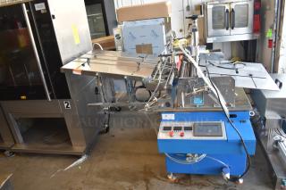 Commercial paper tube labeling machine, blue and stainless steel, displays control panel. Operates at 208/250 Volts, 1 Phase.