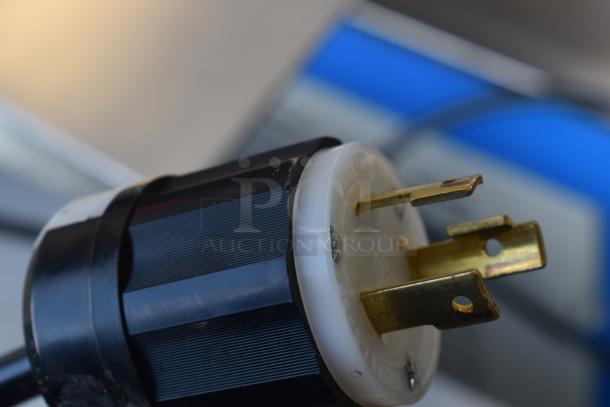 Close-up of a plug for a commercial paper tube labeling machine, 208/250 volts, 1 phase. Visible prongs, black casing.