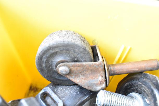 Lot of 20 items including worn commercial caster in a yellow bin. Rust and dirt present, suggests use.