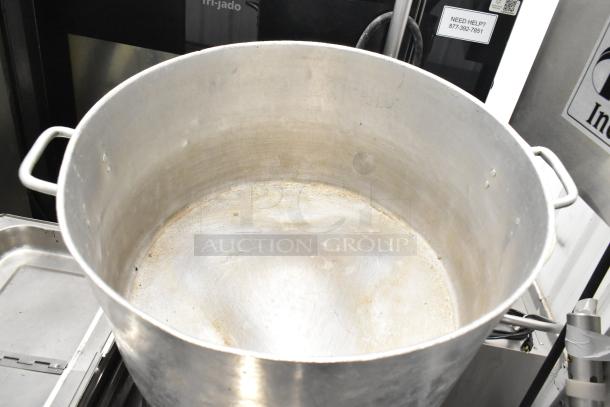 Large aluminum stock pot with handles, showing signs of use. Included in auction lot of 8 items with bins.