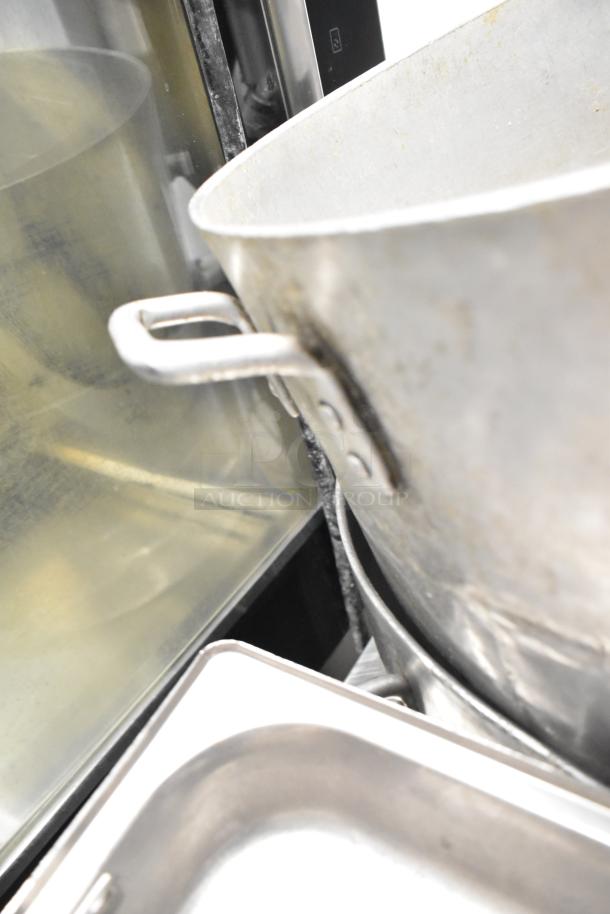 Eight assorted kitchen items, including three stock pots and drop-in bins. Visible wear on pots, metal handles, industrial use.