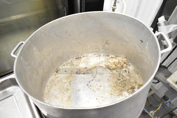 Large used stock pot with visible residue inside, metal handles, and a tarnished surface. Part of an 8-item lot.