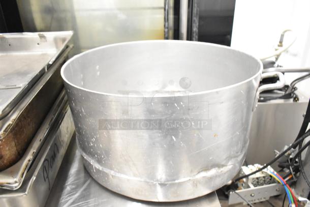 Metal stock pot with visible wear and scratches, alongside stacked cooking trays labeled "Pan Box," part of eight-item auction set.