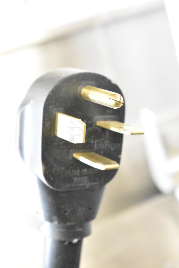 Close-up of a heavy-duty electrical plug for Turbochef HhC2020 oven, black with gold prongs, suited for 208/240V, 3-phase.