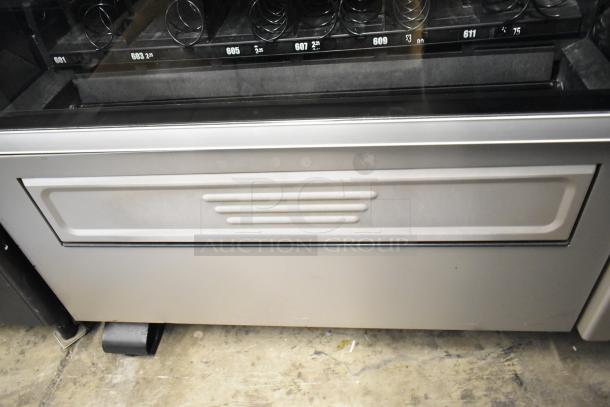 Crane 181 commercial floor vending machine, 115 volts, 1 phase, metal construction, spiral snack dispensers visible, good condition.