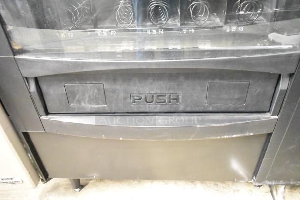 Crane 167 commercial vending machine, floor style, 115 volts, 1 phase. Features black exterior with visible dispensing spirals.