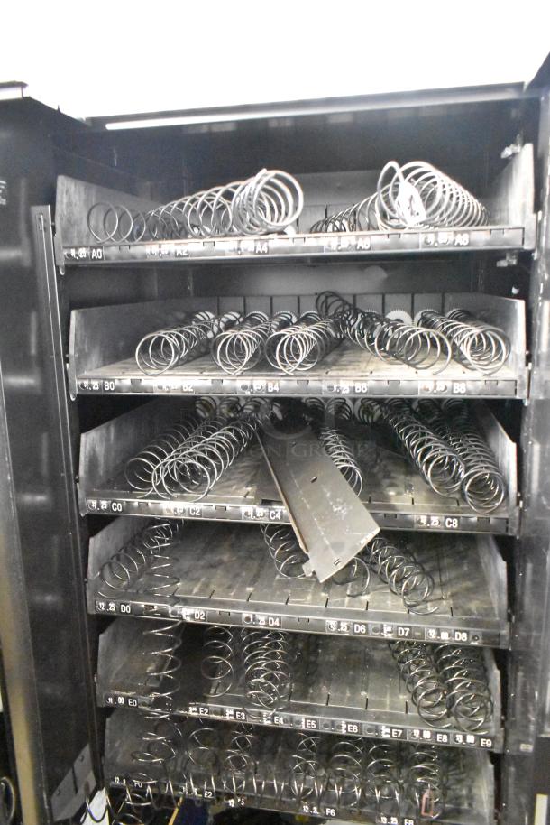 Crane 167 commercial vending machine, floor style, visible coil rows, black interior, labeled slots, 115V, 1 phase.