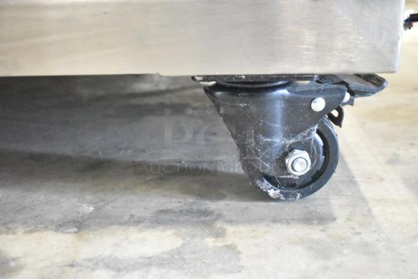 Commercial dough sheeter caster detail, showing durable black caster attached to stainless steel base, indicating mobility.